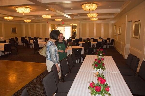 Lilum florist Sari, putting centerpieces out for wedding reception.  Red roses in teapots.