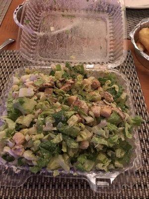 Shredded lettuce for a Caesar salad with very little chicken and bottled dressing