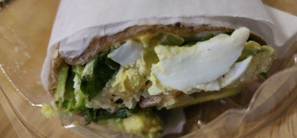 Egg salad wrap with lettuce, tomato, and avocado.