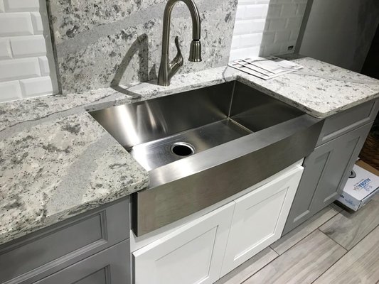 Stainless steel farm sink installed in white shaker cabinet along with luxury Cambria quartz.