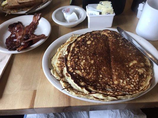 Pancakes, bacon and coffee. In the back-2 eggs, toast, sausage and hash browns.