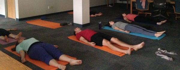 Employees relaxing in Savasana after a lunchtime yoga class at Woodard & Curran.