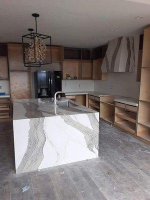 Kitchen island with waterfall and vein flow with matching hood wrap.