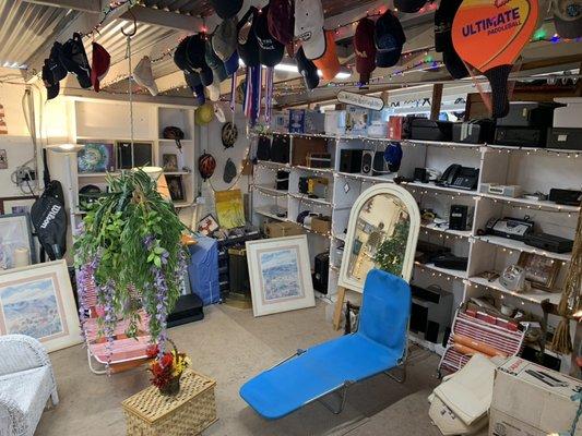 Hats, printers and picture frames inside furniture room.