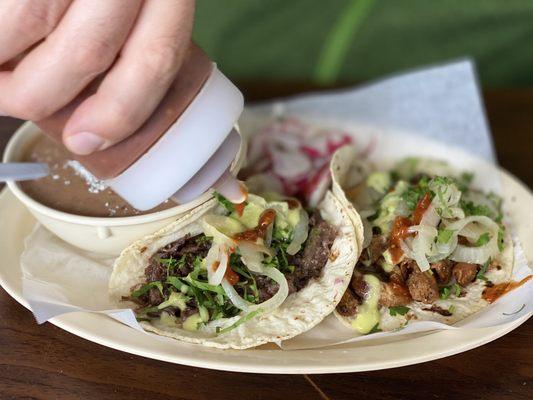 Barbacoa taco, tripas taco on corn with a side of beans