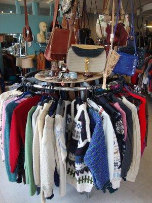 A rack with vintage tops, belt buckles, and purses.