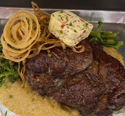 Cast Iron Seared Rib Eye with cheesy polenta, garlic sautéed broccoli rabe, crispy onion strings, and bacon compound butter- special