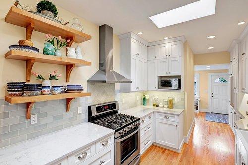 Remodel of a long, skinny kitchen with open, wood shelving and skylights.