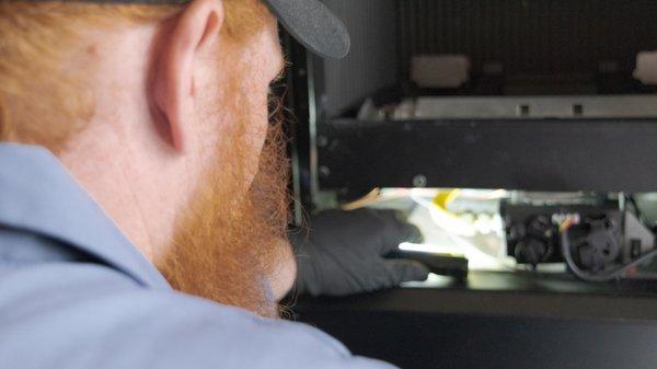 An NFI-Gas Certified technician performs service on a portrait-style fireplace.