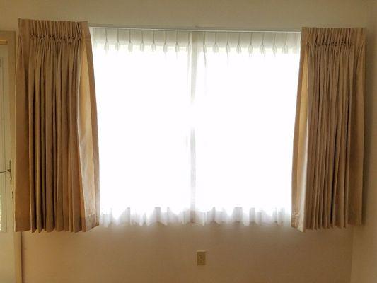 Pinch pleat drapes with sheets underneath.