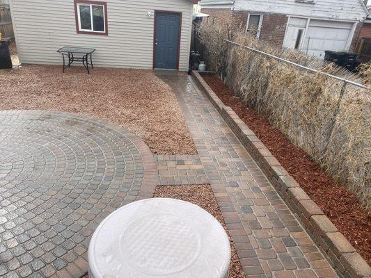 Paver patio and crushed rock installation with a block planter bed.