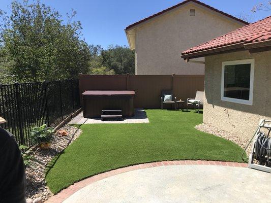 We installed a beautiful paver pad for our customers jacuzzi and surrounded it with our premium turf. Cobble stones accented the boarders.