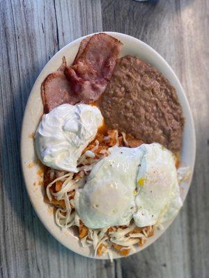 Chilaquiles with choose and two runny eggs on top with sour cream on the side