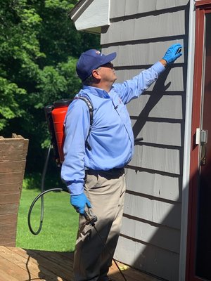 Catseye's professional pest control technician spraying exterior of home.