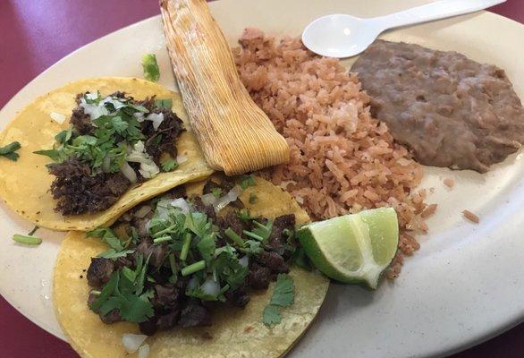 Taco plate with a Barbacoa Taco, another brisket taco, a tamale and rice and beans