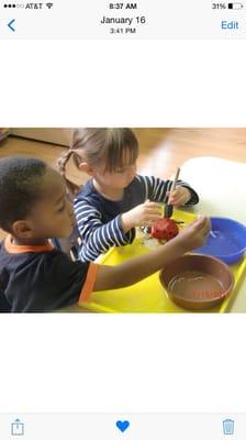 Two preschoolers at an activity table where there were bugs frozen in blocks of ice. The kids had to thaw out or brake the ice.