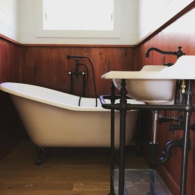 Vintage style claw foot bathtub with telephone style handheld tub fill and decorative freestanding pedastool.