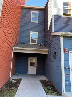 Entrance to building with lovely garbage on roof and in corners