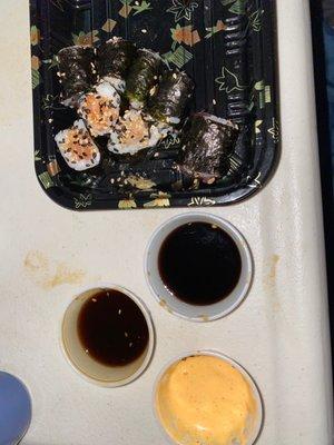 Spicy Mayo, unagi, and soy sauce with sushi rolls.