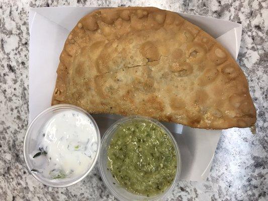 Homemade empanada with a housemade sour cream and salsa verde