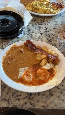 Huevos rancheros with over easy eggs, potato and egg breakfast plate and a side of bacon for the table.