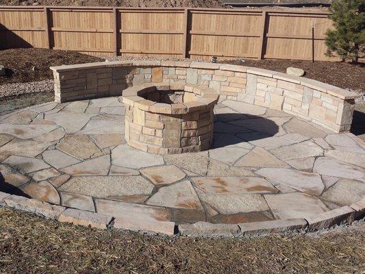 Custom flagstone patio with natuaral brick fire pit and accented with stone wall