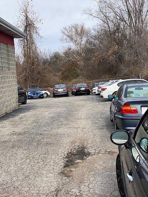 Parking lot is filled with customer BMWs and other cars.