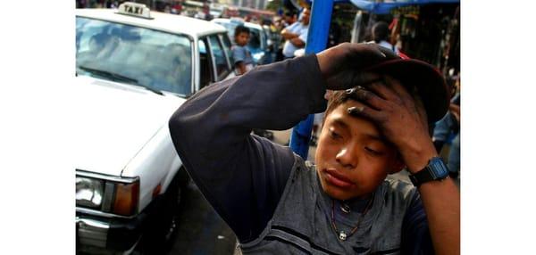 A Guatemalan 'lustrador' or shoe shiners wipes sweat from his young brow