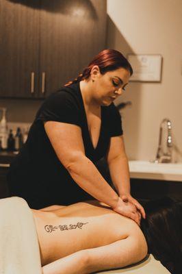 A sports massage therapist works on a client's back and neck.