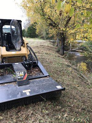 Skid steer bush hog work cleaning up creek banks.