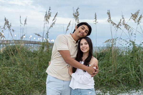 couple photo in the sand dunes with boardwalk and ocean in background