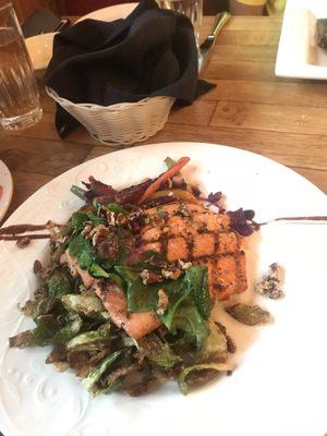 Salmon entree over a grit cake, sautéed greens, and a balsamic butter reduction.