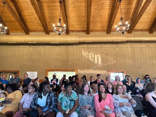 People standing, crowded into a barn.