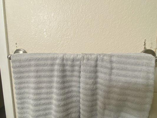 Multiple drill holes in wall above towel bar.