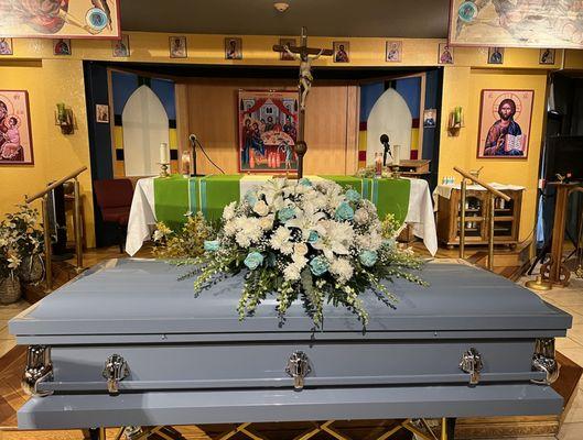 BLUE CASKET WITH WHITE AND BLUE CASKET SPRAY AT A VIEWING