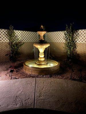 Three tiered fountain with lights in the bottom tier and two spot lights pointed at the top of the fountain. Absolutely gorgeous!