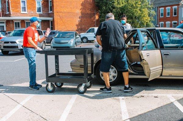 Volunteer bringing food and clothing to car.