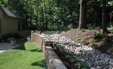 Finished dry river bed to divert water away from the retaining wall to a designated location.