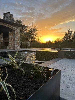 Raised steel beds with a variety of ornamental grasses and plants and black mulch, and amazing lighting