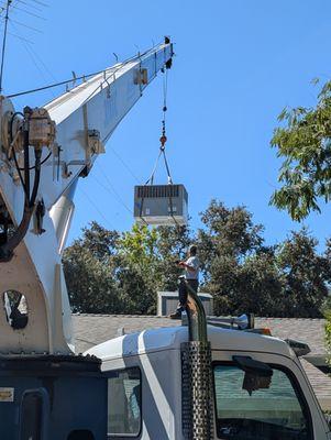 The crane lifting the HVAC on the roof