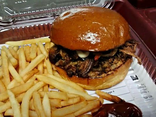 Pulled pork sandwich with chipolte honey bbq sauce and fries.