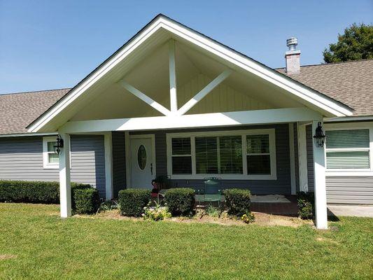 Custom built front porch using 6x6s for the posts, 5.25in wood trim around windows and door, vinyl siding, exterior door installation.