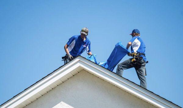 Lyon Home Enterprises roofers tarping a storm struck home