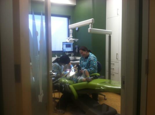 Abigail brushing stuffed animal teeth while being seen by Dr. Chen.