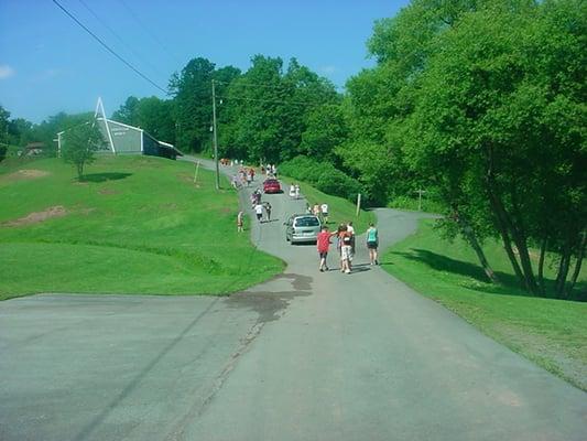 Campers walking up from the pool, pond, and campfire area with the chapel in the background. Picture from www.fifthavecoc.com