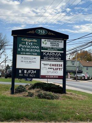 Exterior signage of office. Signage is located between two driveways. Enter where the car wash is.