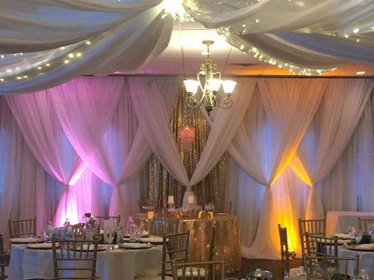 Our rentals included ceiling drapery, backdrop, uplighting, Chiavari chairs, table linens, charger plates, dinnerware and centerpieces.