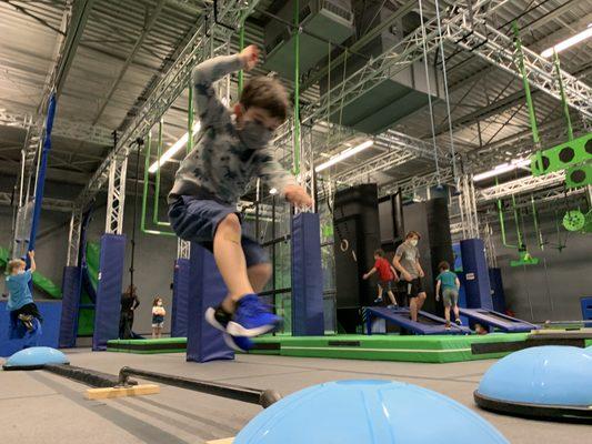 Leaping boy on ninja course.