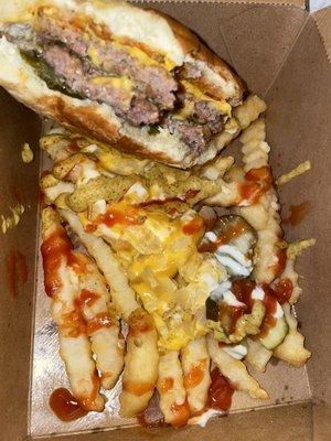 Chomped half Beast burger perched inside container of Beast style fries