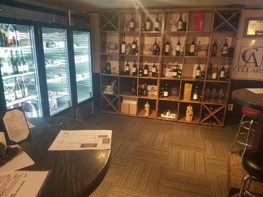 Wine racks for inside/outside consumption along with pizzas, flatbread, cheeses, and sausages from around the Dodge County area for sale.